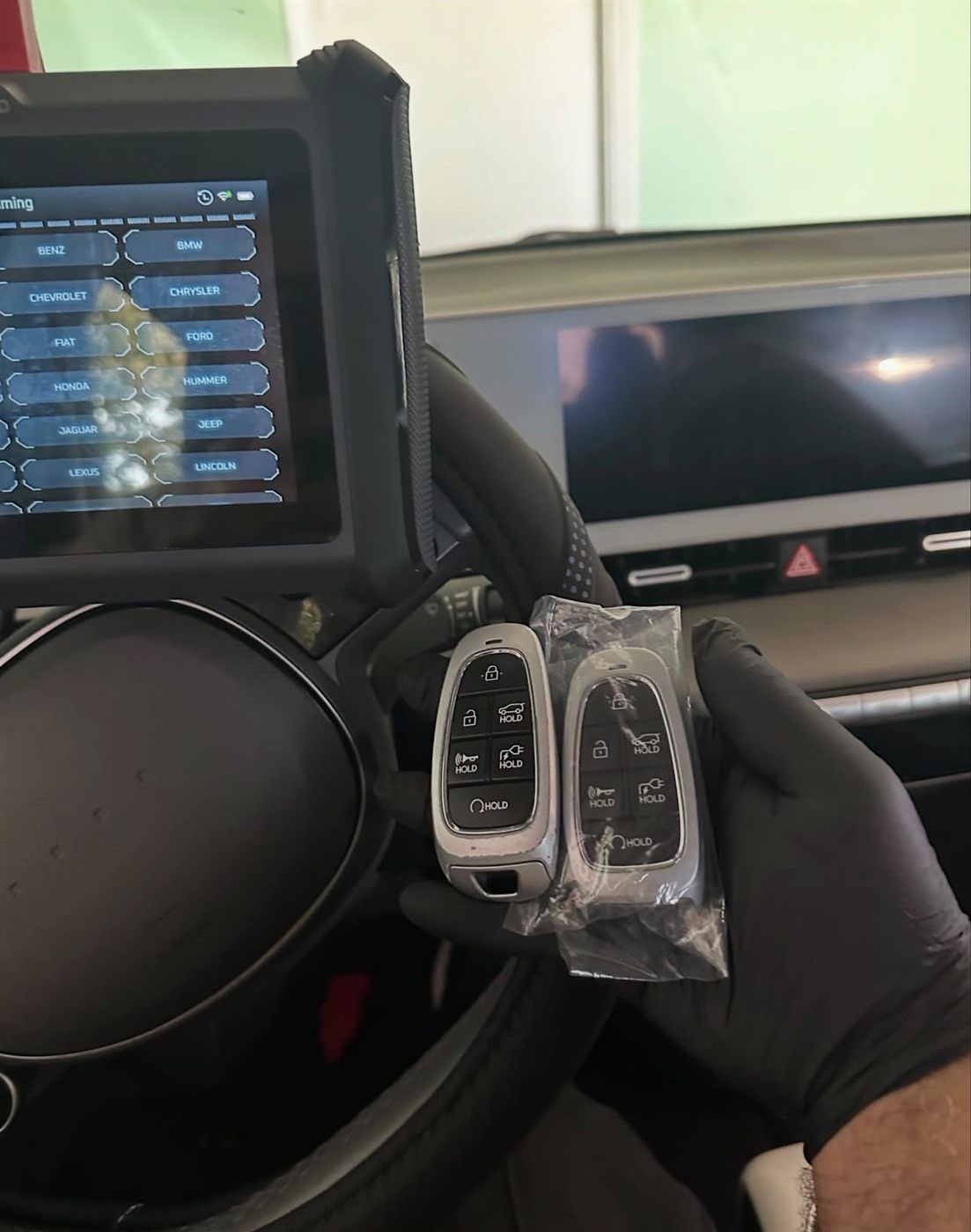 Two push-to-start smart keys being programmed with a diagnostic tablet inside a car