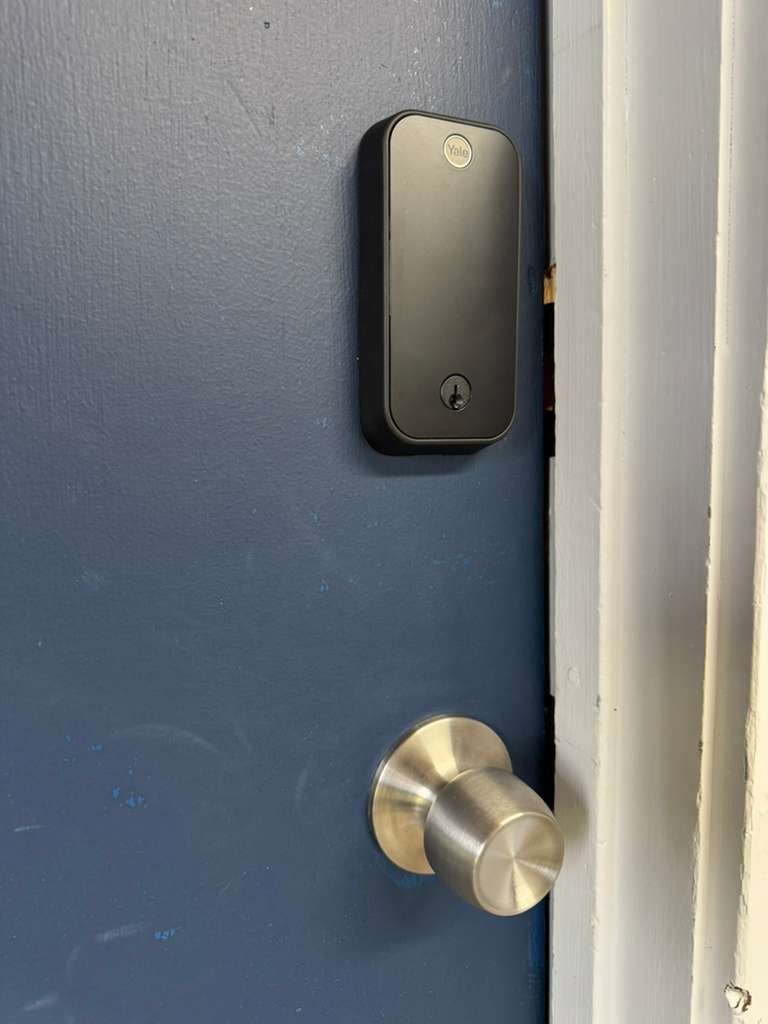 Smart deadbolt installed above a door knob on a blue door