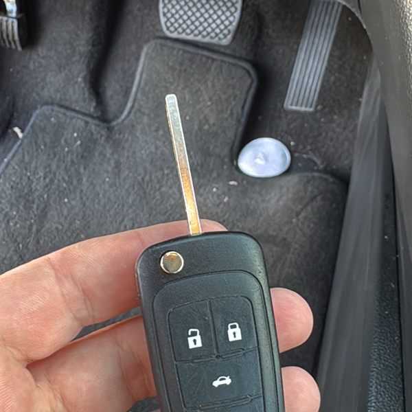 New flip key remote held inside a car near the pedals