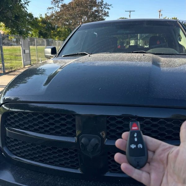New key fob held in front of a black pickup truck