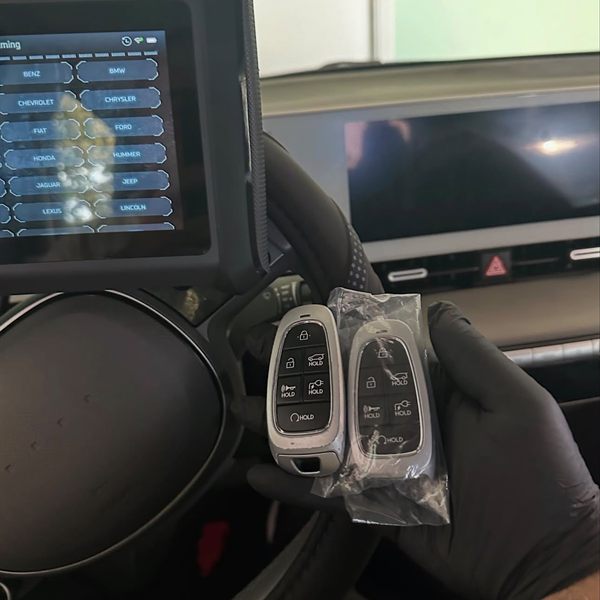 Two push-to-start smart keys being programmed with a diagnostic tablet inside a car