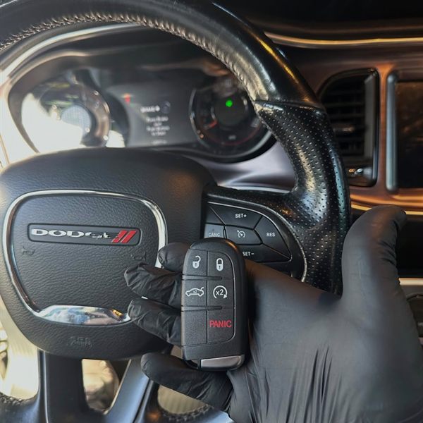 New push-to-start smart key held in front of a steering wheel