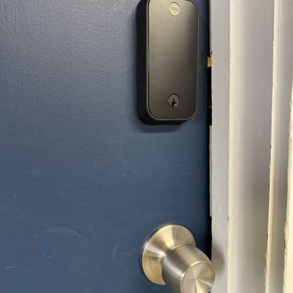 Smart deadbolt installed above a door knob on a blue door