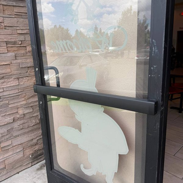 Black panic bar installed on a glass storefront door